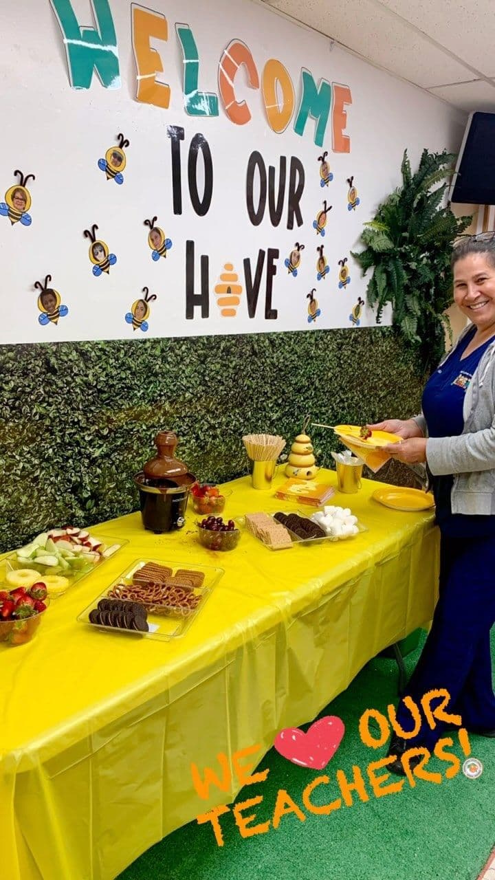 A Kiddie Corner teacher at a Teacher Appreciation celebration under a Welcome to Our Hive display.